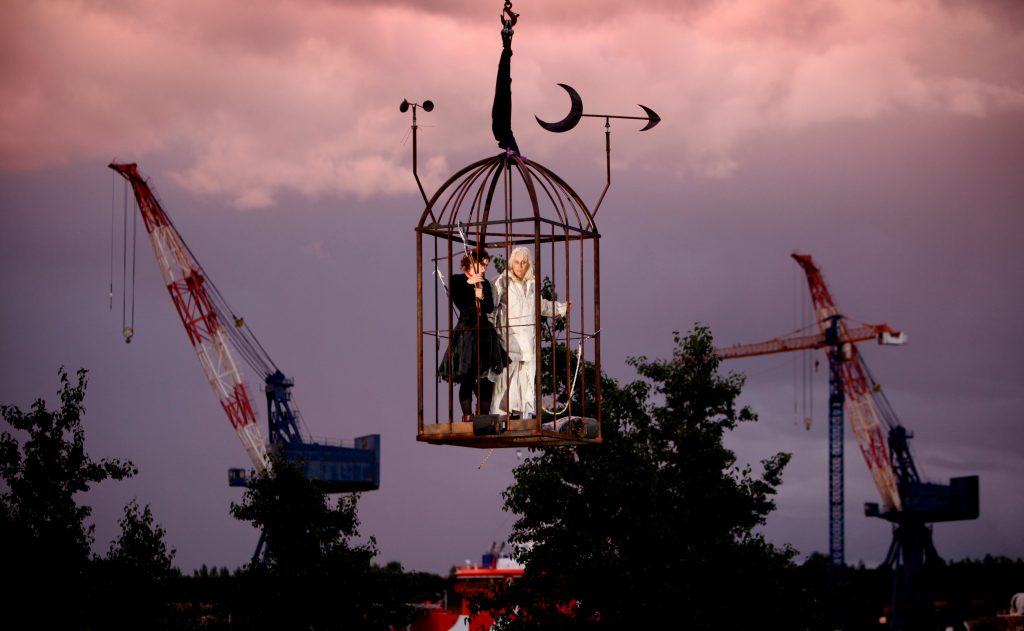 Two performers are in a huge cage suspended in the air. A Beautiful Journey by Wildworks