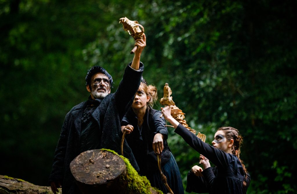 Wolf's Child by Wildworks. Performers in the woods holding animal skulls. 