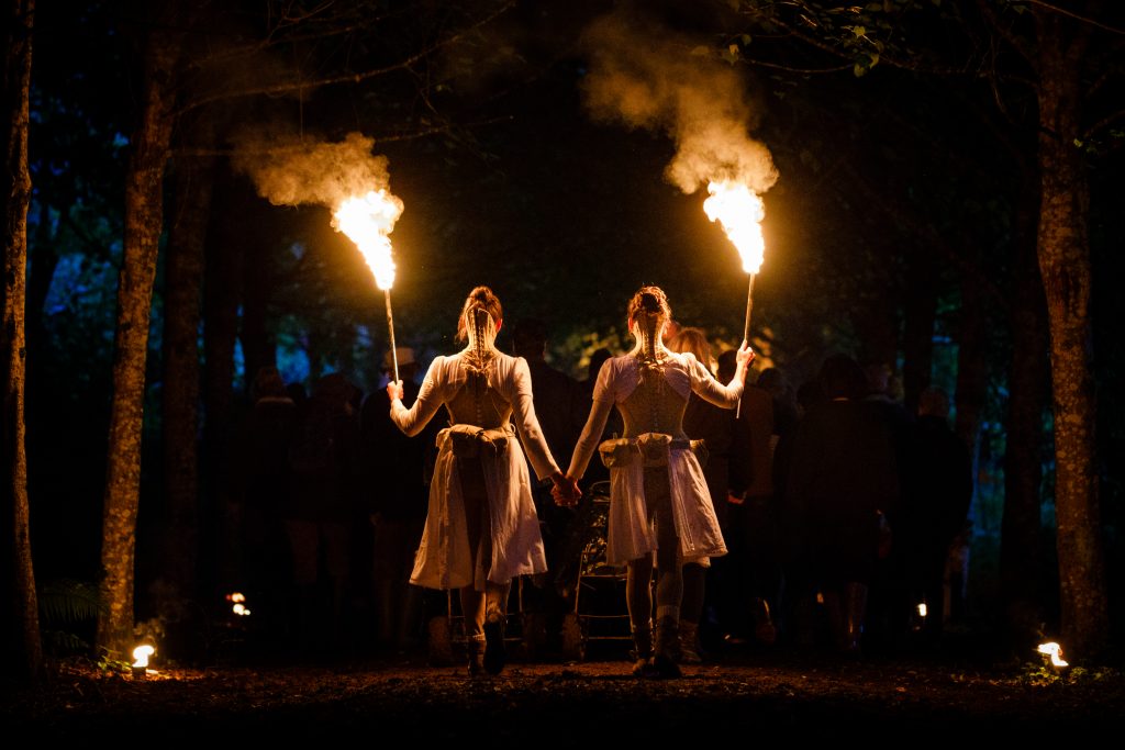 Two performers in Wolf's Child by Wildworks. Holding flaming torches 