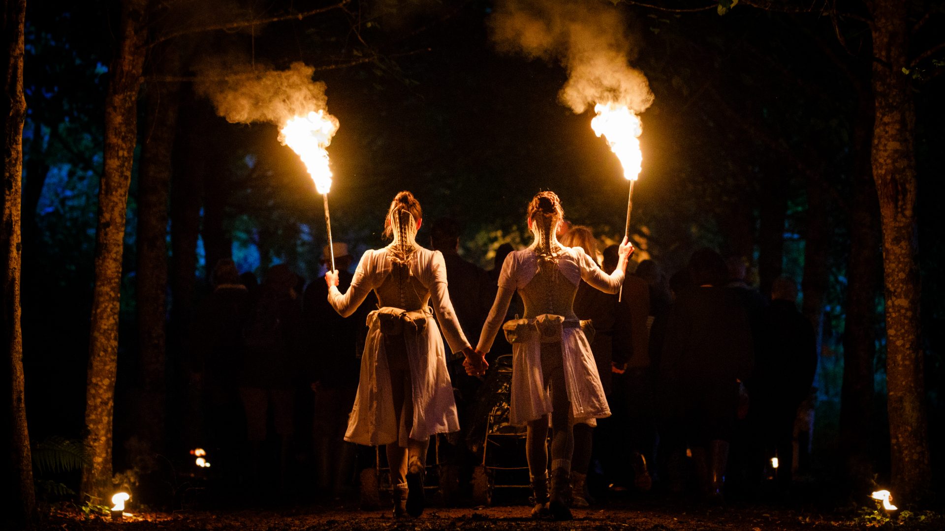 Two performers in Wolf's Child by Wildworks. Holding flaming torches