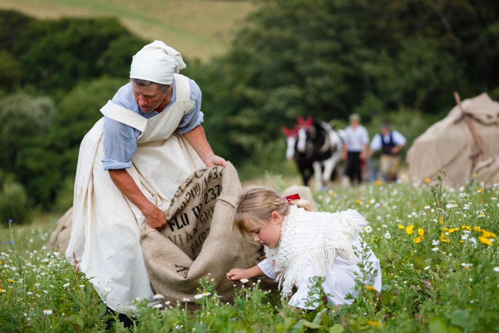 Women and children in a field. 100: The Day Our World Changed by Wildworks.