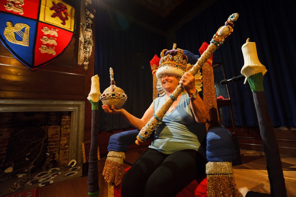 A person sits on a knitted throne as part of Enchanted Palace by Wildworks