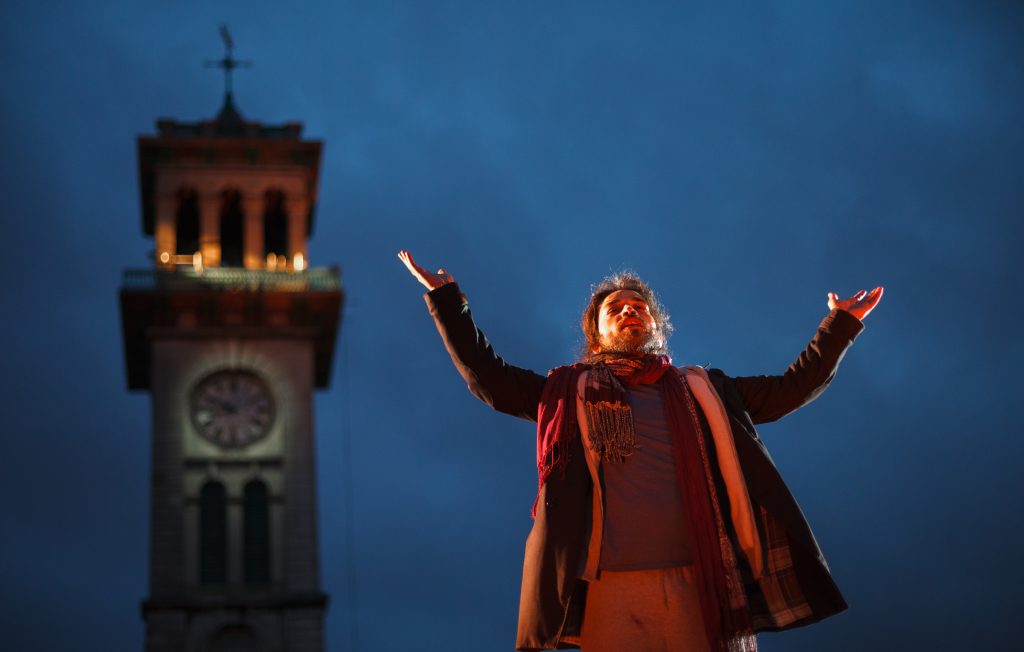A person stands in front of a clock tower - Bable by Wildworks