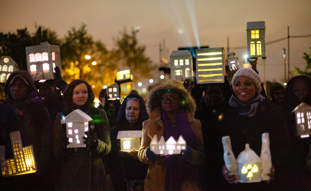 A group of people hold lanterns in the dark. Babel by Wildworks