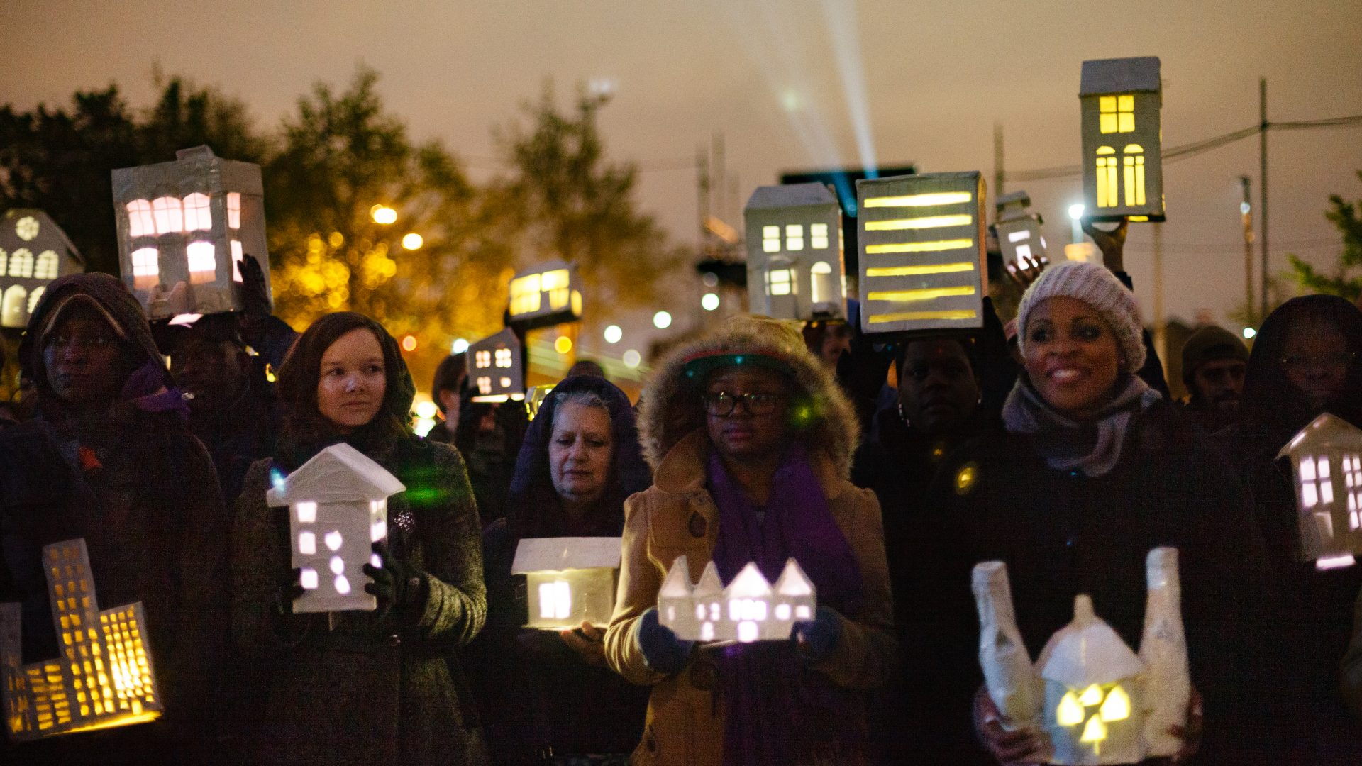 A group of people hold lanterns in the dark. Babel by Wildworks