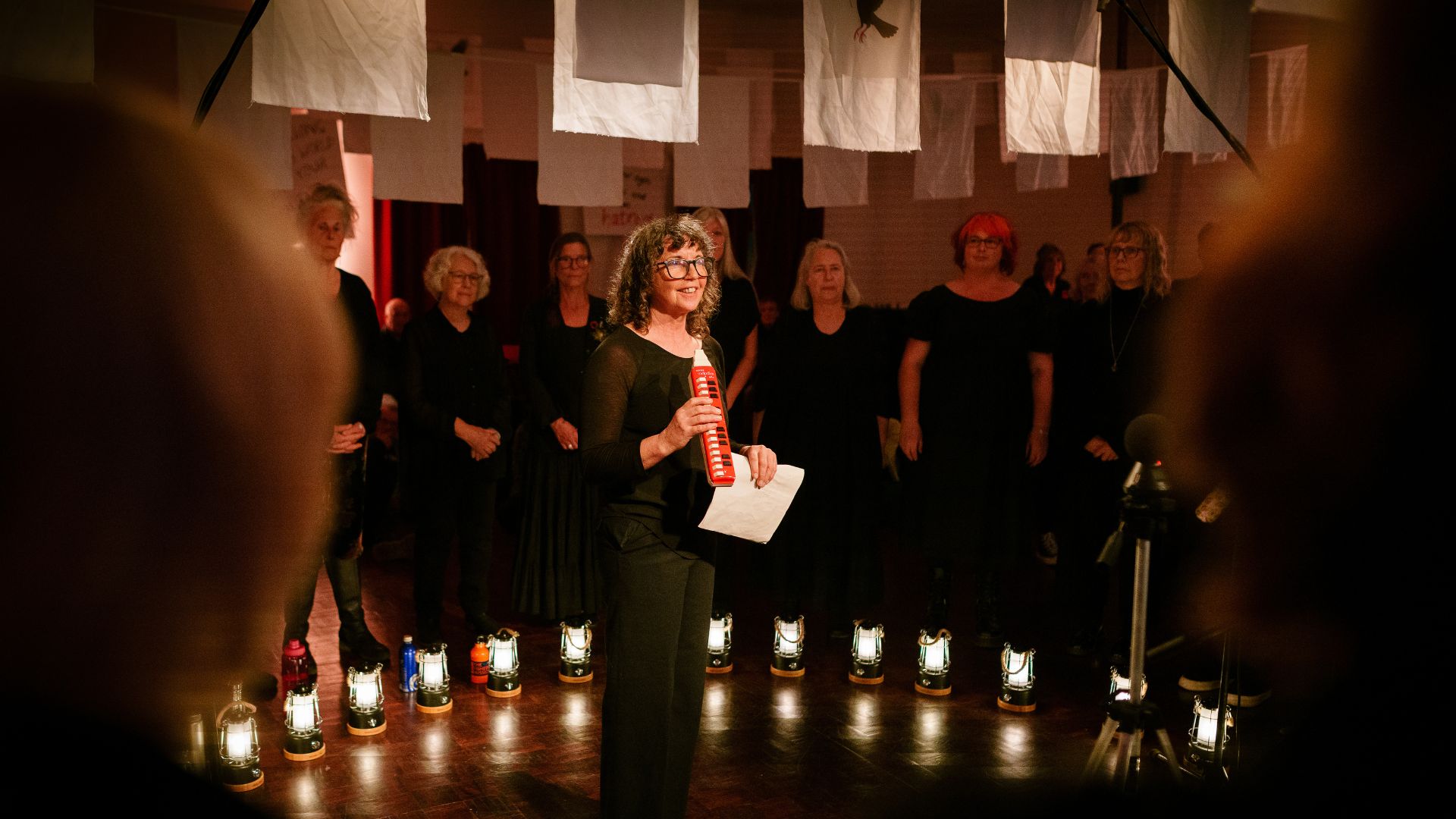 Vicky Abbot stands in the centre of a circle of Blend Choir From West Cornwall to the West Bank by Wildworks.