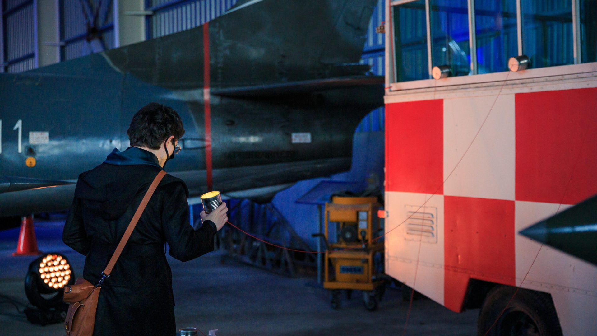 A man holds a tin can with a string attached as part of the installation for Arrow of Time in Malta.