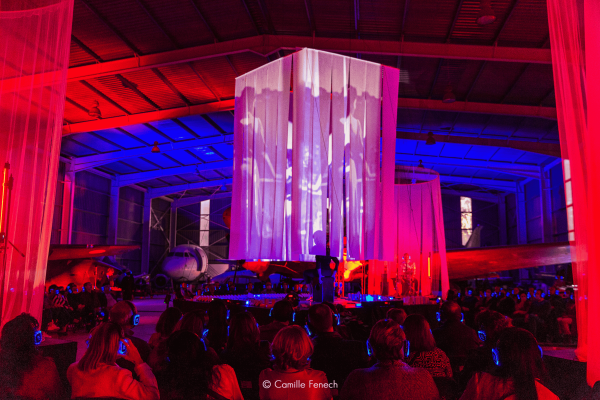 A stage with fabric suspended above it, a film is projected onto the sheet of fabric.